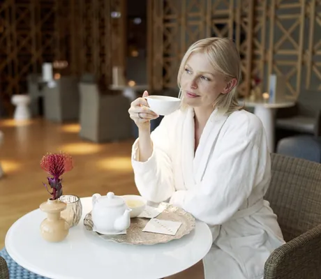 Frau trinkt im Bademantel eine Tasse Tee