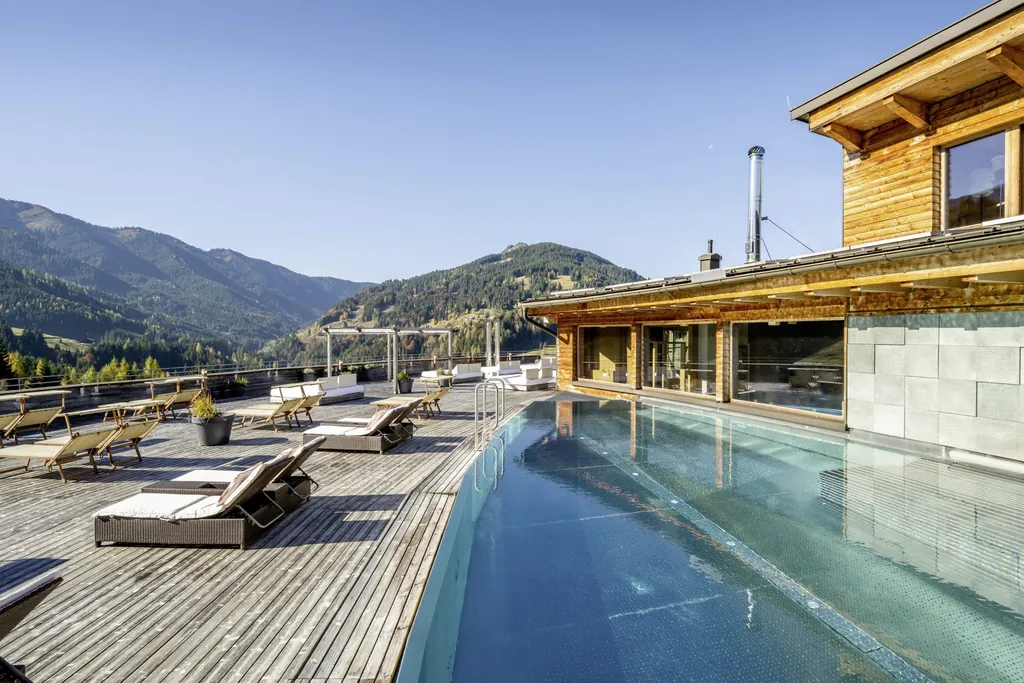 Rooftoppool mit Sonnenliegen und Sicht auf die Berge