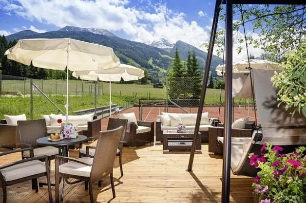 Terrasse mit Tennisplatz und Bergblick im Hotel Sonngastein im Sommer