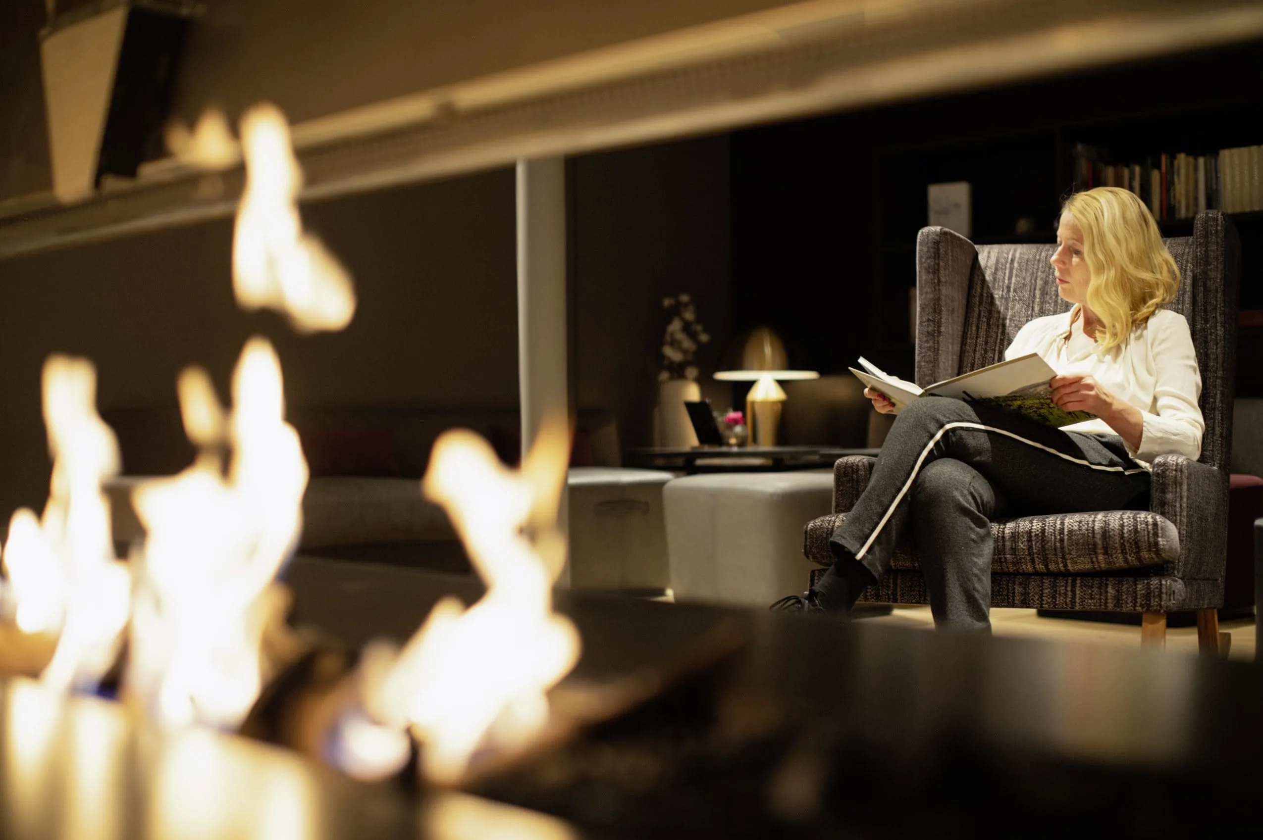 Lesende Frau in der Tagesbar bei Kaminfeuer im Der Oeschberghof