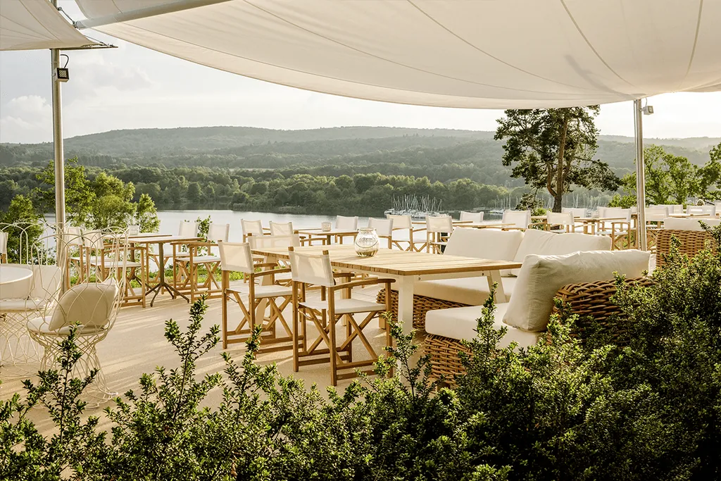 Terrasse mit moderner Bestuhlung, Segeldach und Blick auf Bostalsee der Seezeitlodge