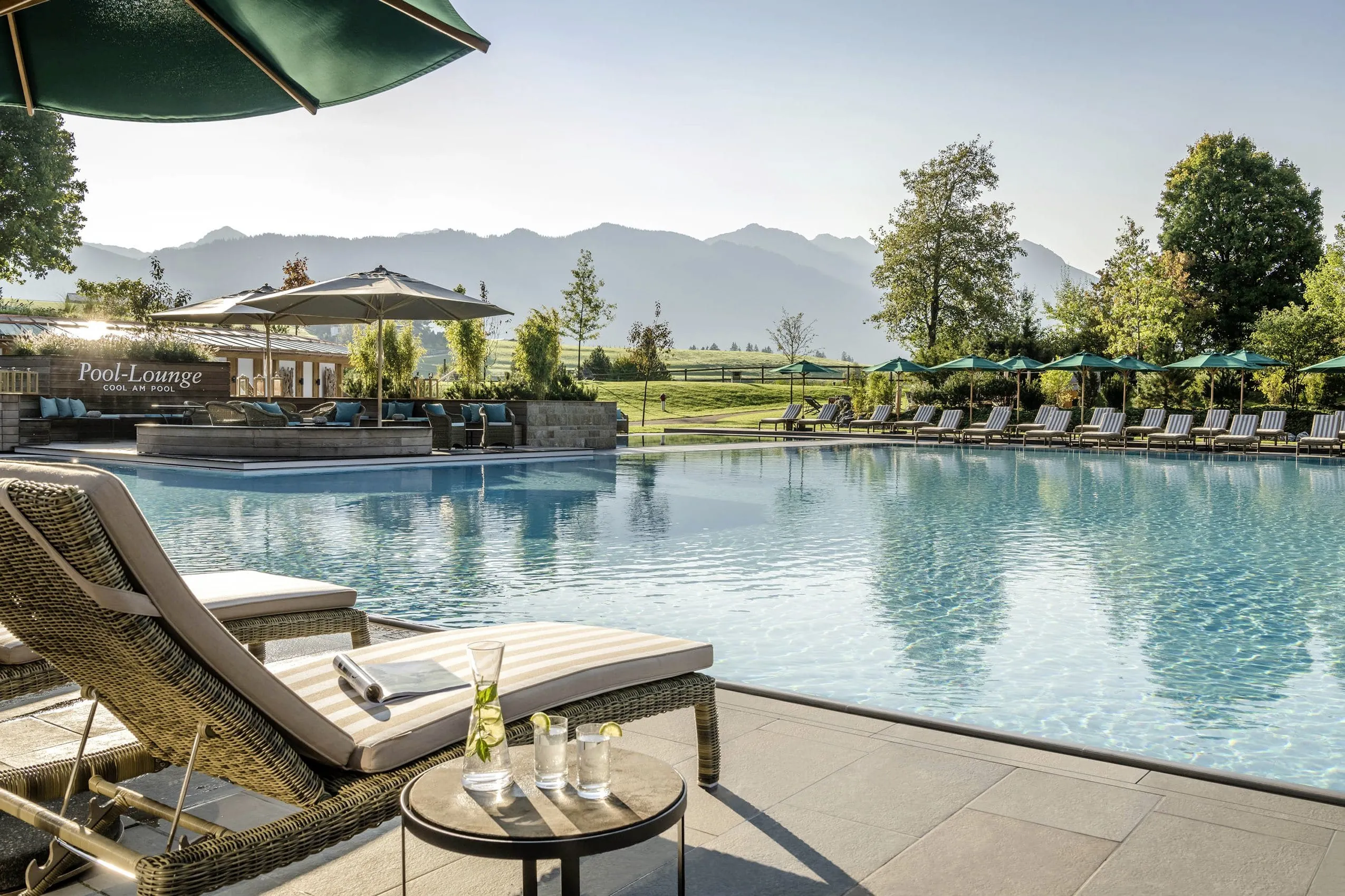 Aussenpool mit Bestuhlung und Bergblick des Sonnenalp Resort im Sommer