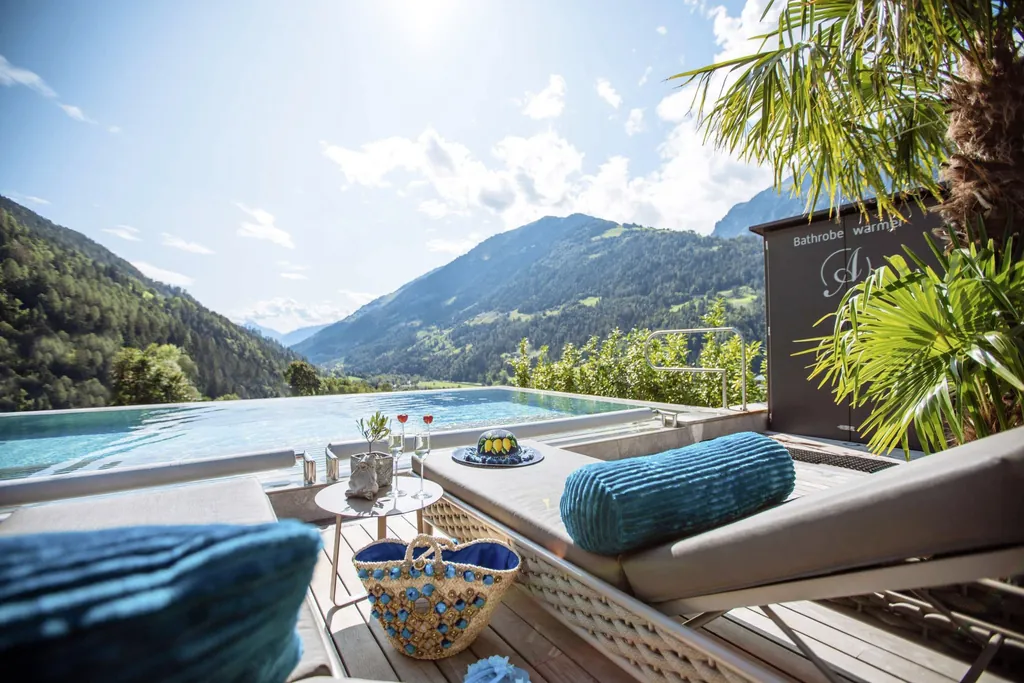 Rooftop-Pool mit Liegen, Sekt, Korbtasche und Blick auf die Berge