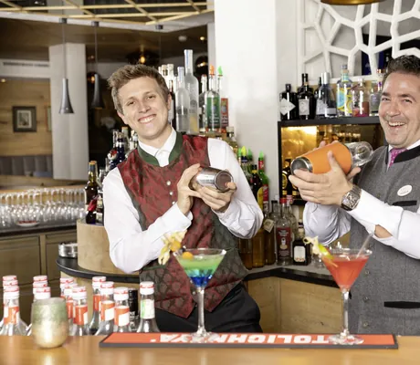 zwei Männer an der Bar mixen lachend Cocktails im Alpbacherhof