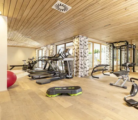 Fitnessraum mit Holzboden und gemusterten Gardinen im Alpbacherhof