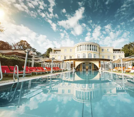 Außenpool vor Außenansicht und dramatischem Wolkenspiel im Hotel Bei Schumann