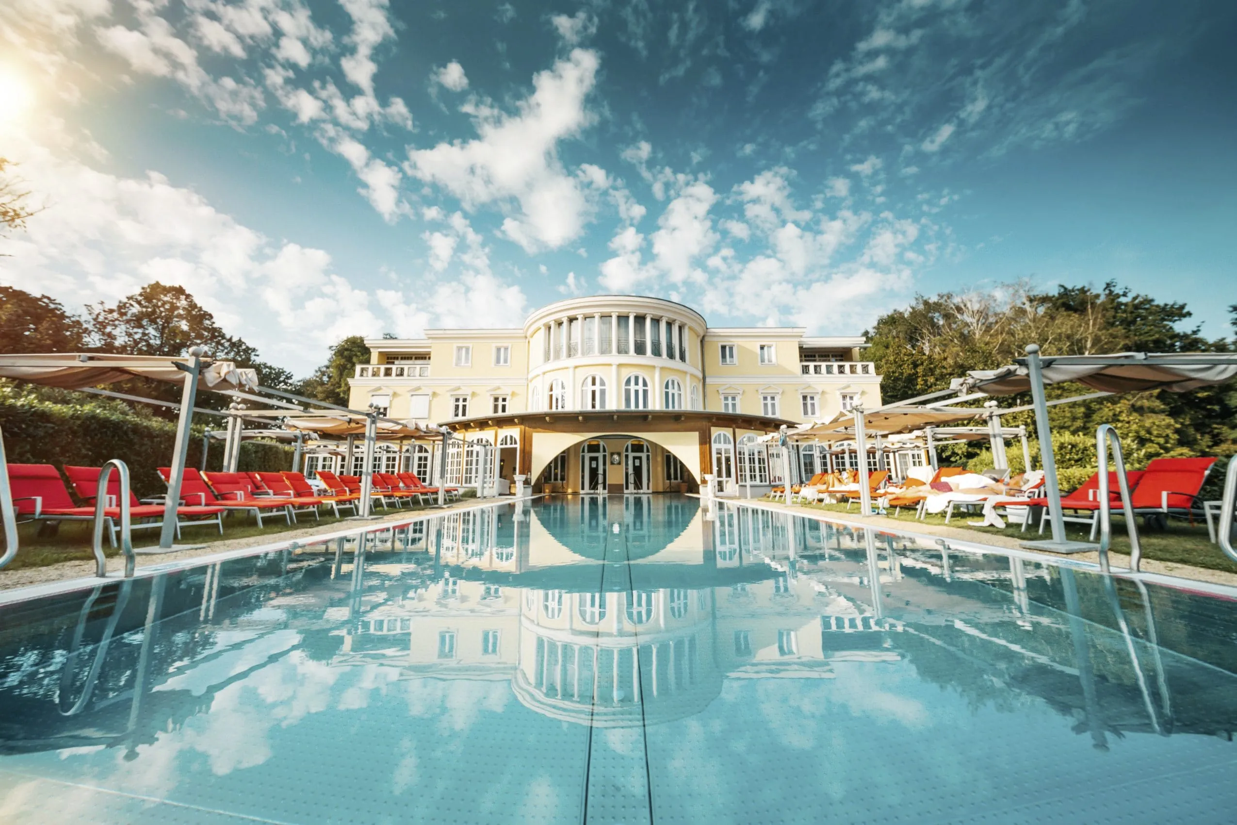 Außenpool vor Außenansicht und dramatischem Wolkenspiel im Hotel Bei Schumann