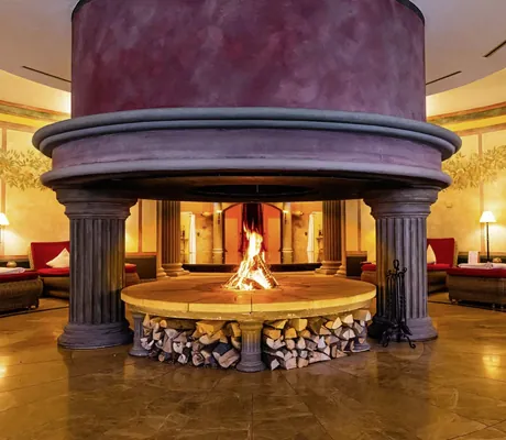 riesiger runder offener Kamin in römischer Optik im Ruheraum des Hotel Bei Schumann