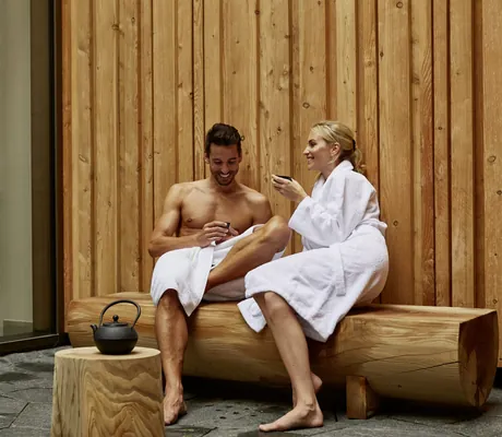 Pärchen im Bademantel trinkt Tee auf Holzbank des Spa im Öschberghof