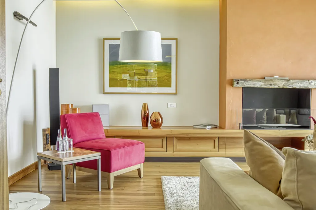 Zimmerausschnitt mit rotem Sessel und Kamin im Wald- & Schlosshotel Friedrichsruhe