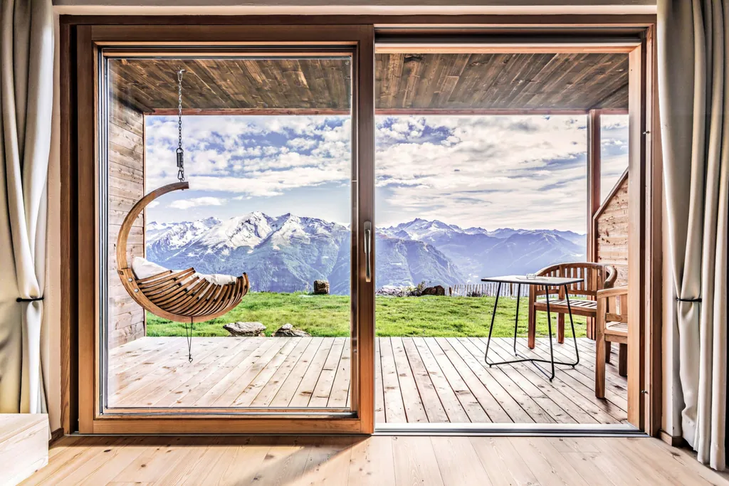 Blick durch die großen Panoramafenster im Chalet Stern auf den Balkon und die gegenüberliegenden Berge Südtirols