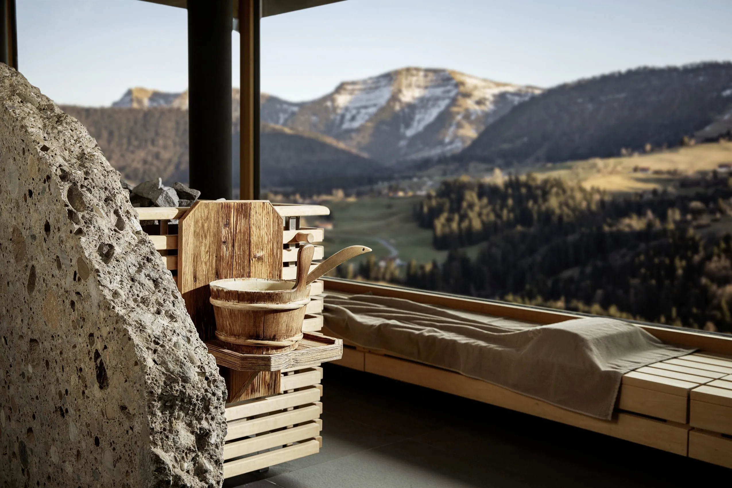 Blick aus der Panoramasauna des Bergkristall Resort mit gro&szlig;en Fensterfronten auf die umgebenden Berge