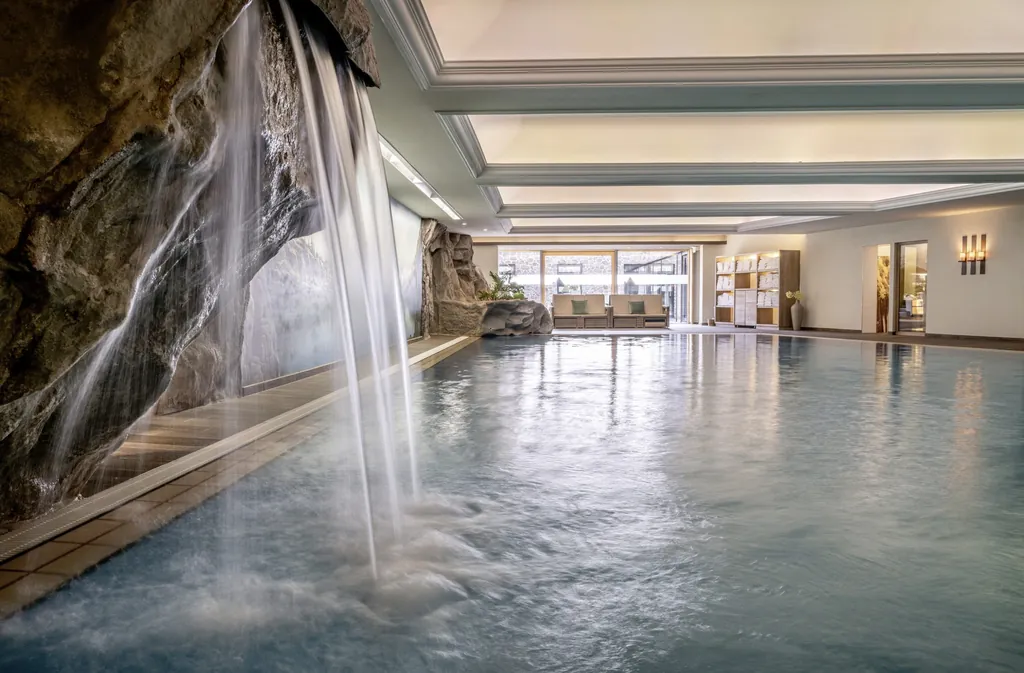 Indoorpool mit kleinem Wasserfall und harmonischer Lichtstimmung im Hotel Franks