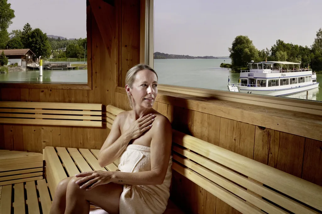 Frau sitzt in Finnischer Panoramasauna mit Blick auf den Forggensee im Hotel Sommer