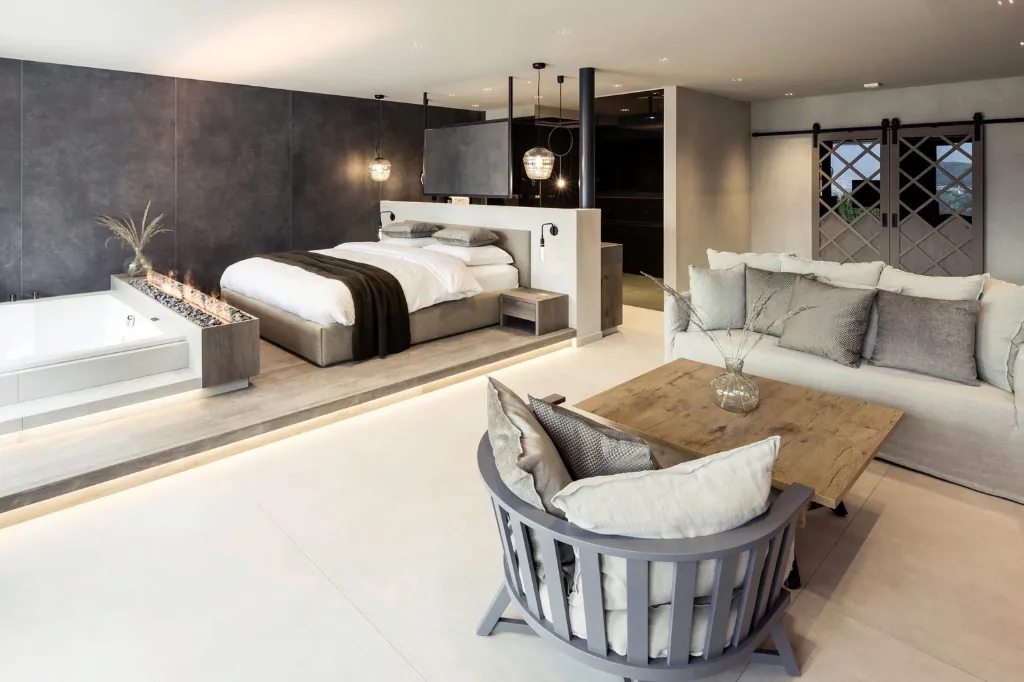 Innenansicht mit Bett, Sofa und ebenerdiger Badewanne im Luxus-Chalet Purmontes