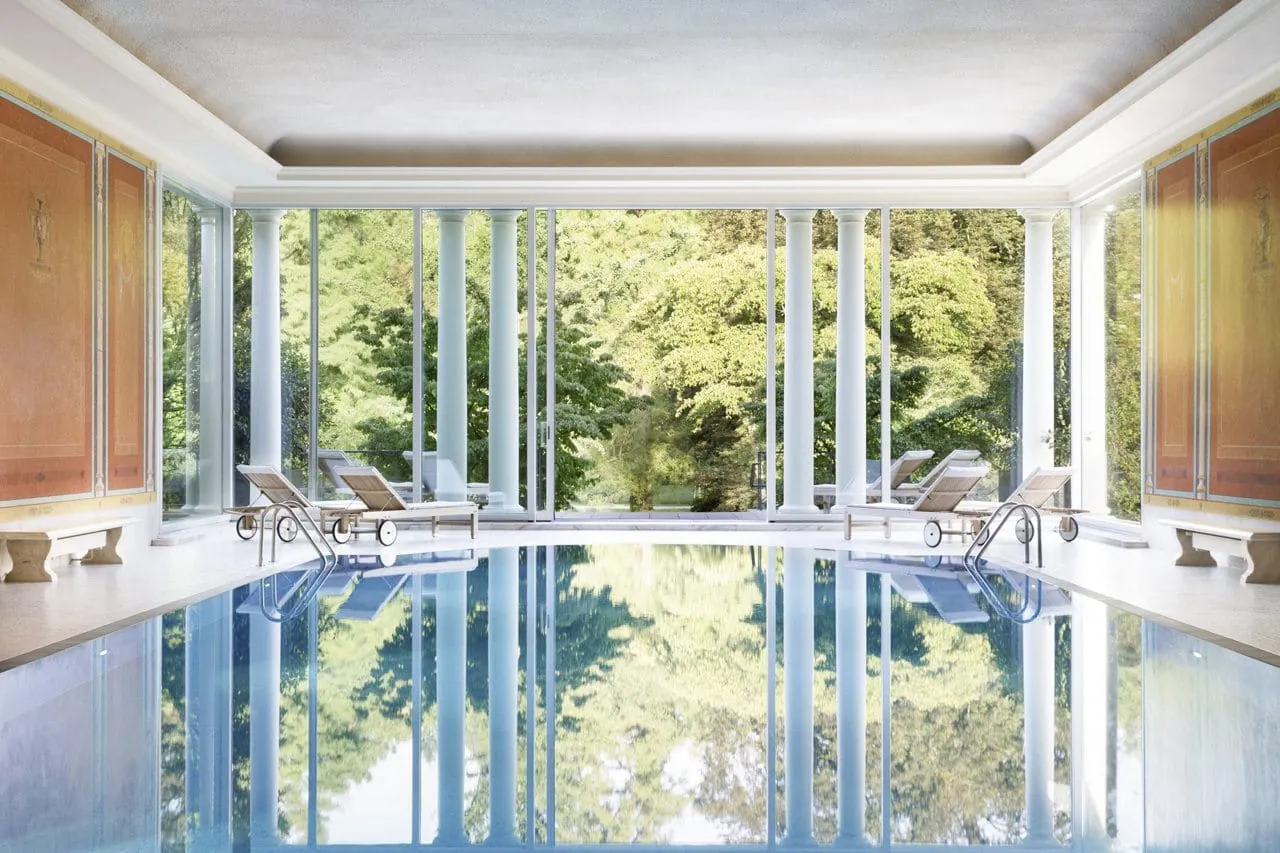 Indoorpool mit orangen W&auml;nden und Blick ins Gr&uuml;ne in Brenners Park-Hotel