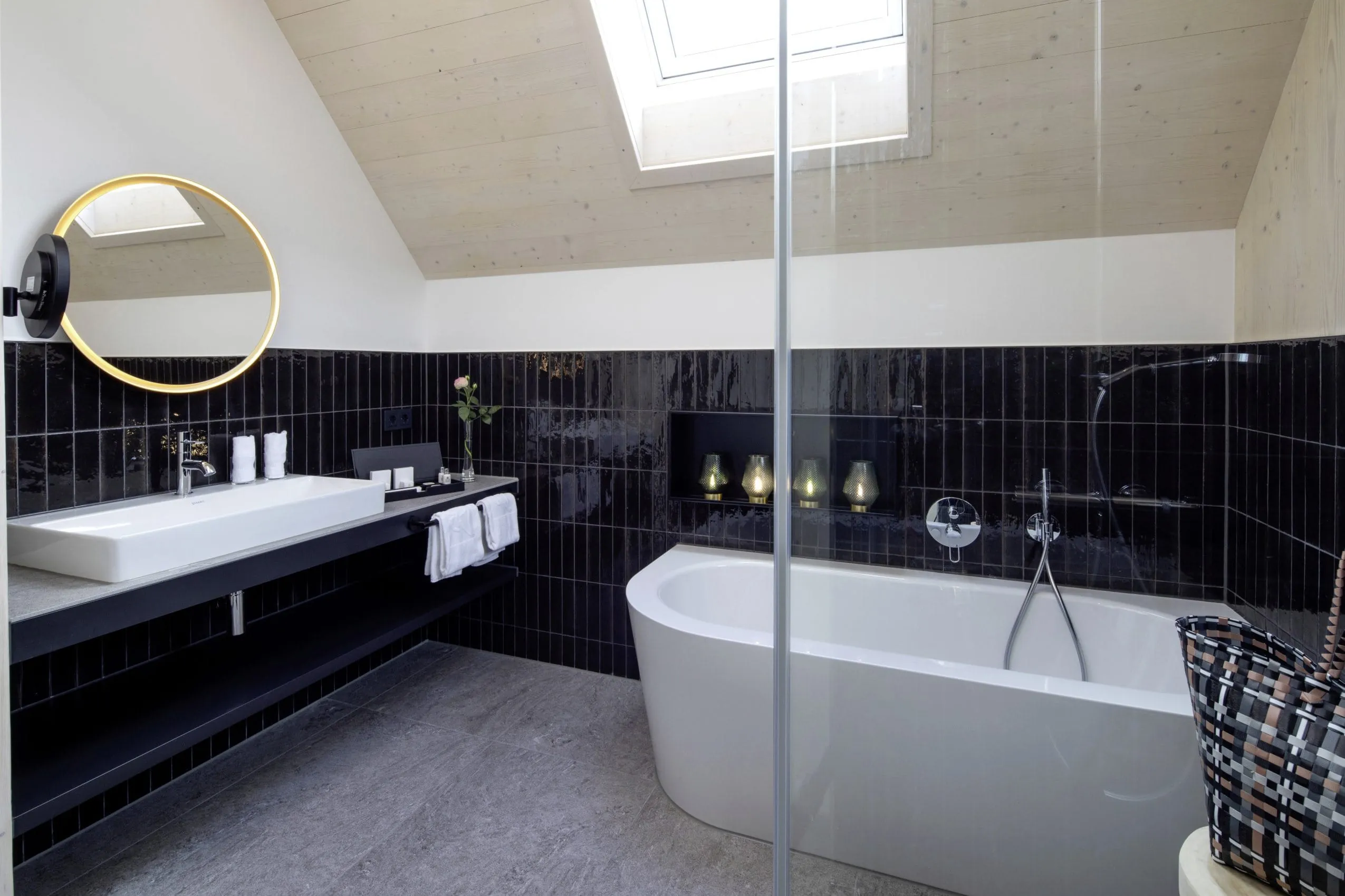Badezimmer mit schwarzen Fliesen und Badewanne im Luxus-Wellnesshotel Hotel Engel Obertal