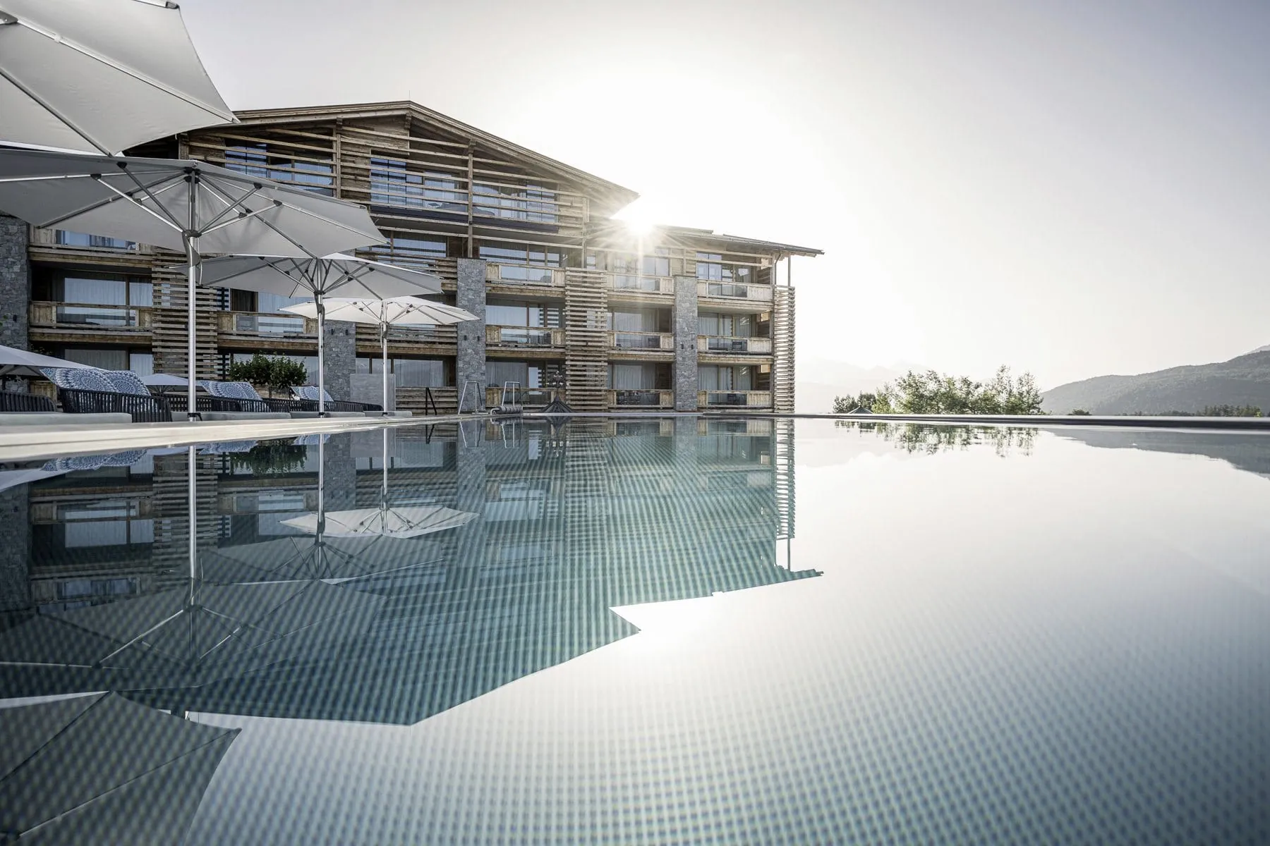 Au&szlig;enpool mit Sonnenschirmen im Alpenresort Schwarz in &Ouml;sterreich