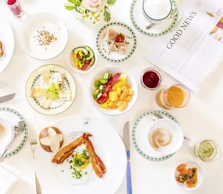 gedeckter Frühstückstisch mit Bacon und Obst von oben im Wald- & Schlosshotel Friedrichsruhe