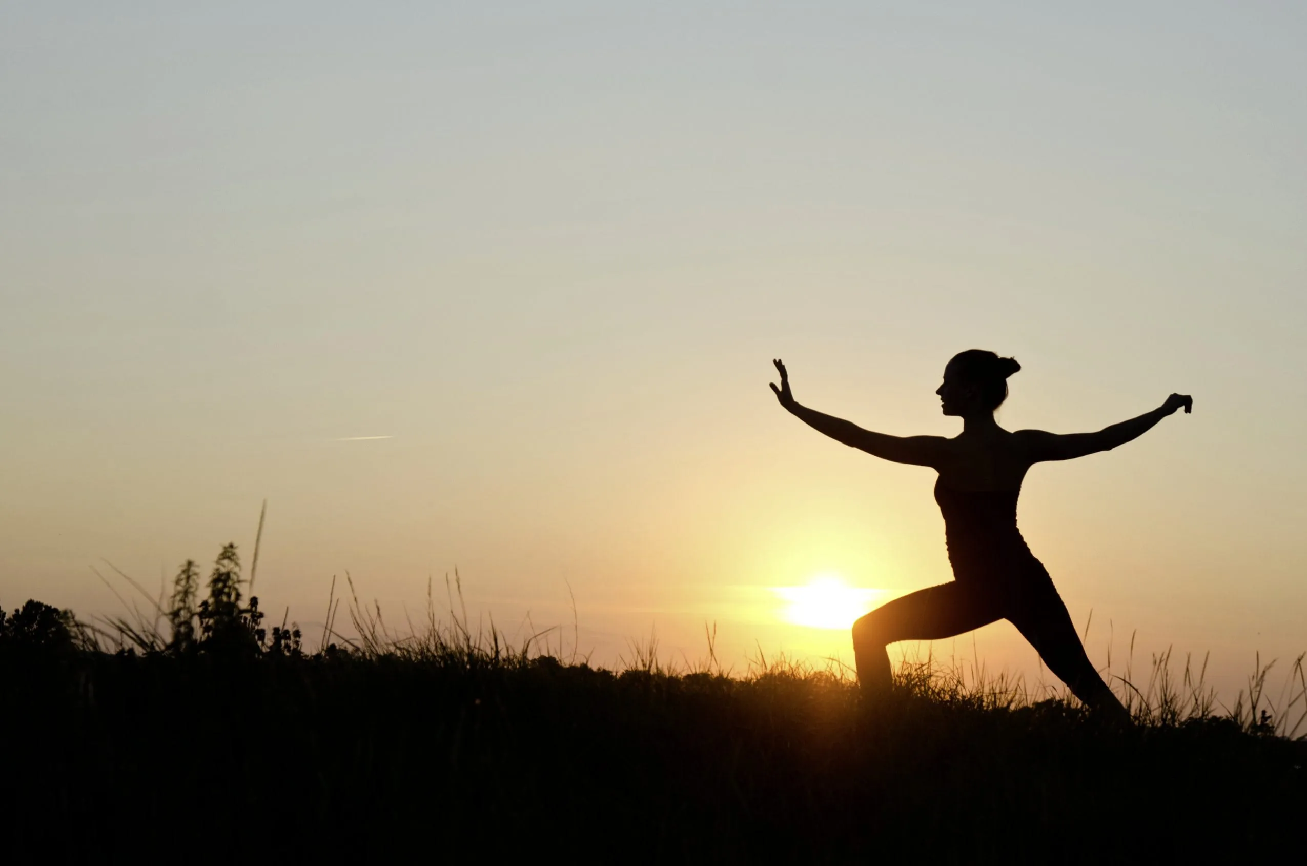Frau praktiziert Tai Chi im Sonnenuntergang