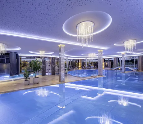 verschiedene Becken im Indoorpoolbereich mit Kristalllüstern im Wellness- & Sporthotel Jagdhof