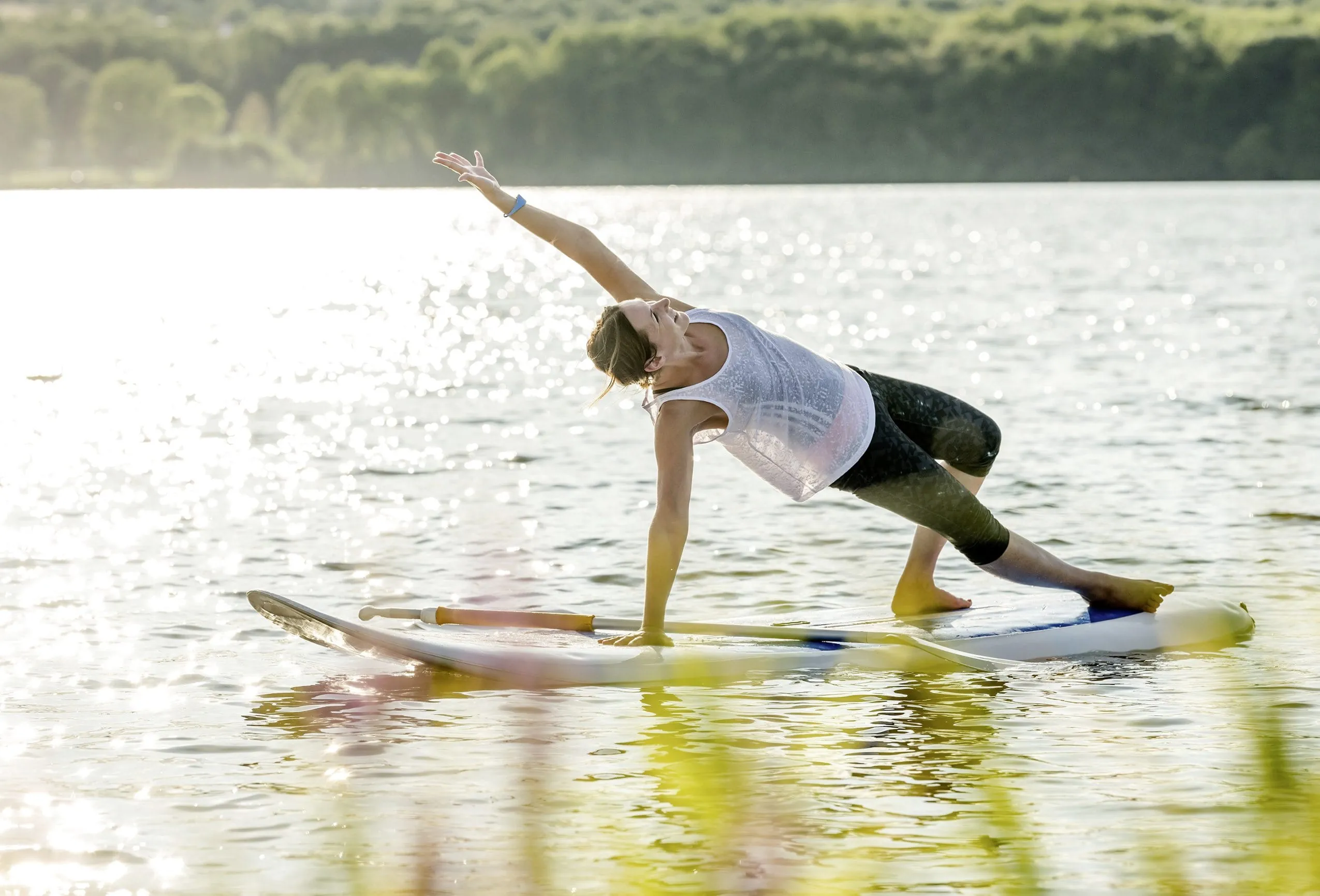Frau macht Yoga auf dem Stand Up Paddelboard auf dem See der Seezeitlodge