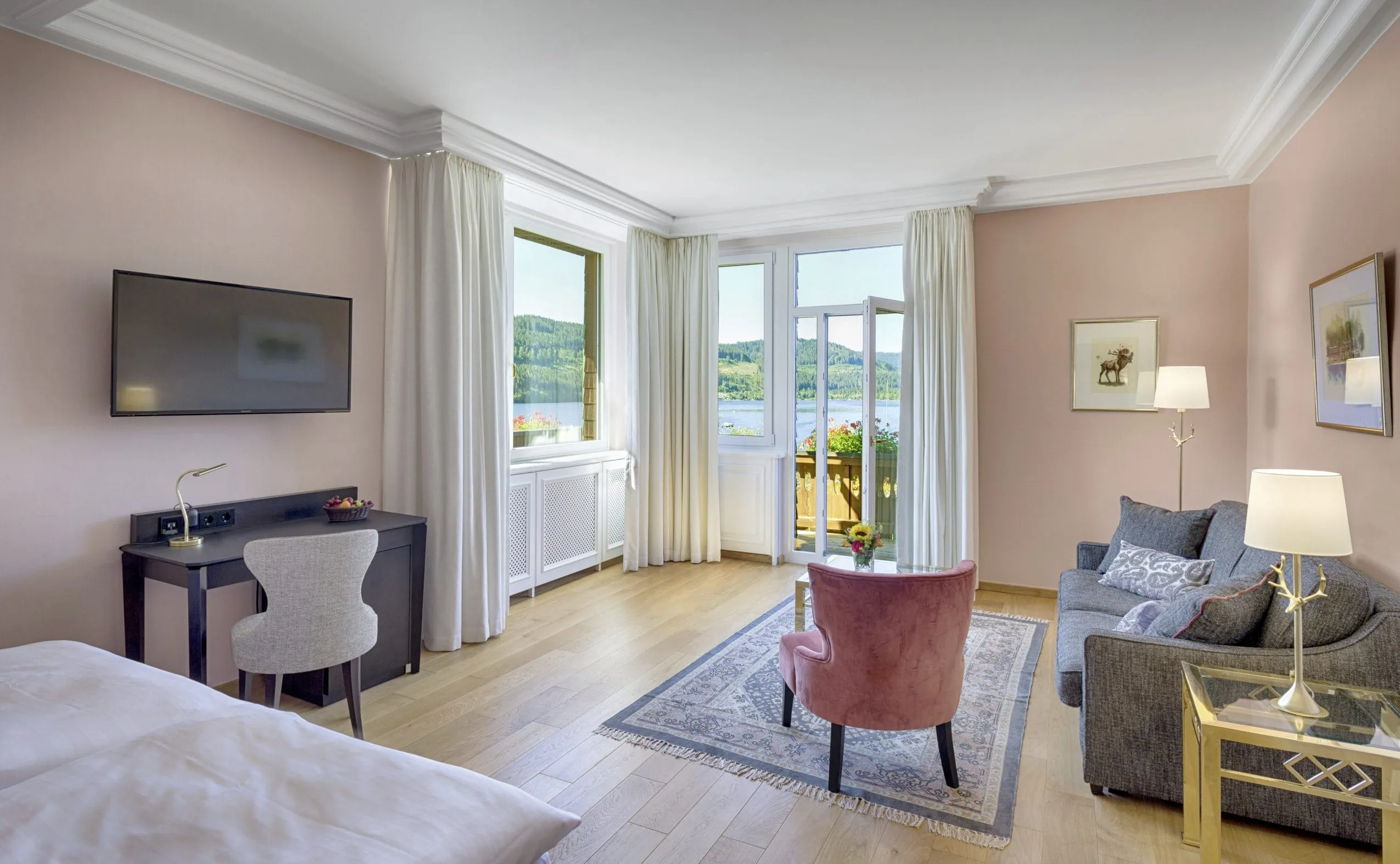 hochwertig m&ouml;bliertes Eckzimmer mit altrosa Sessel und Blick auf den See in Treschers Schwarzwaldhotel