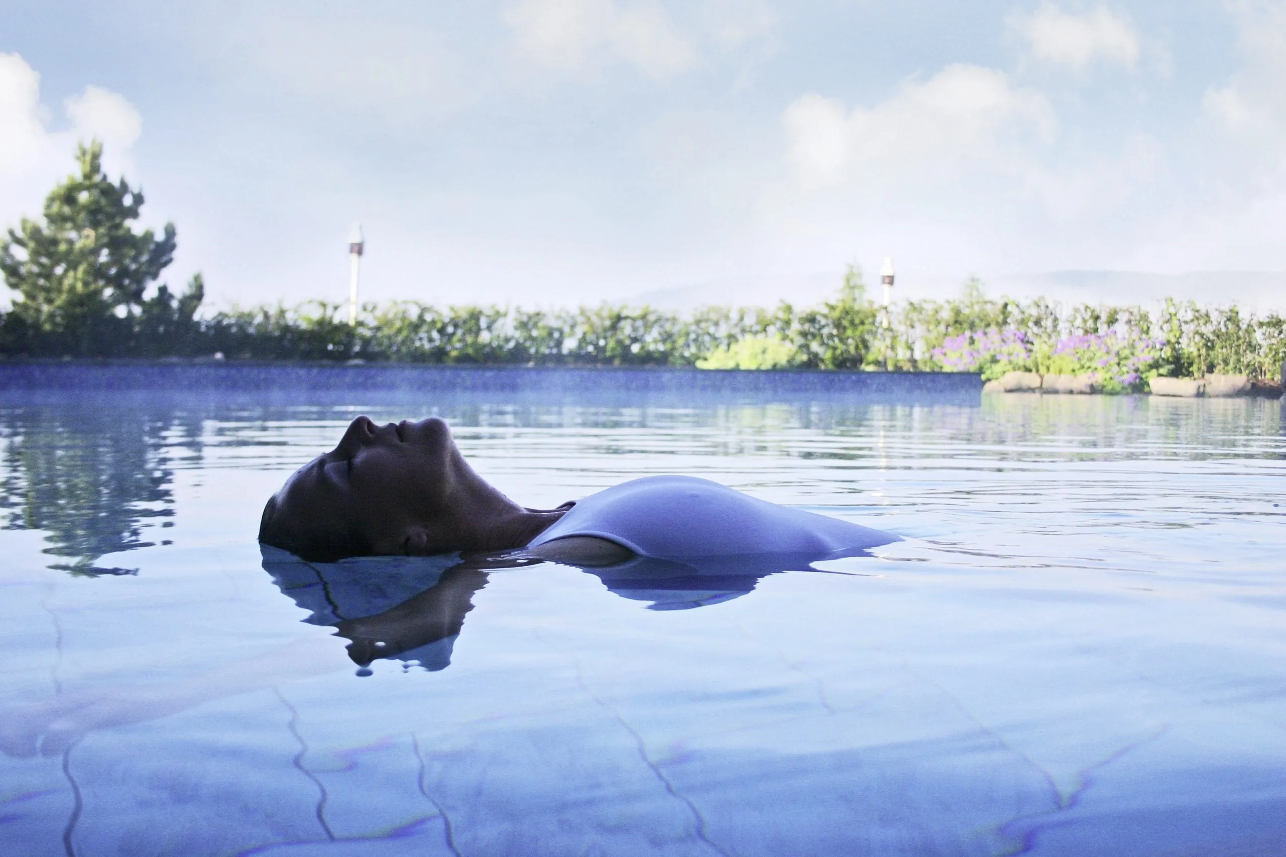 Frau im wei&szlig;en Badeanzug floatet im Outdoorpool des Vier Jahreszeiten am Schluchsee