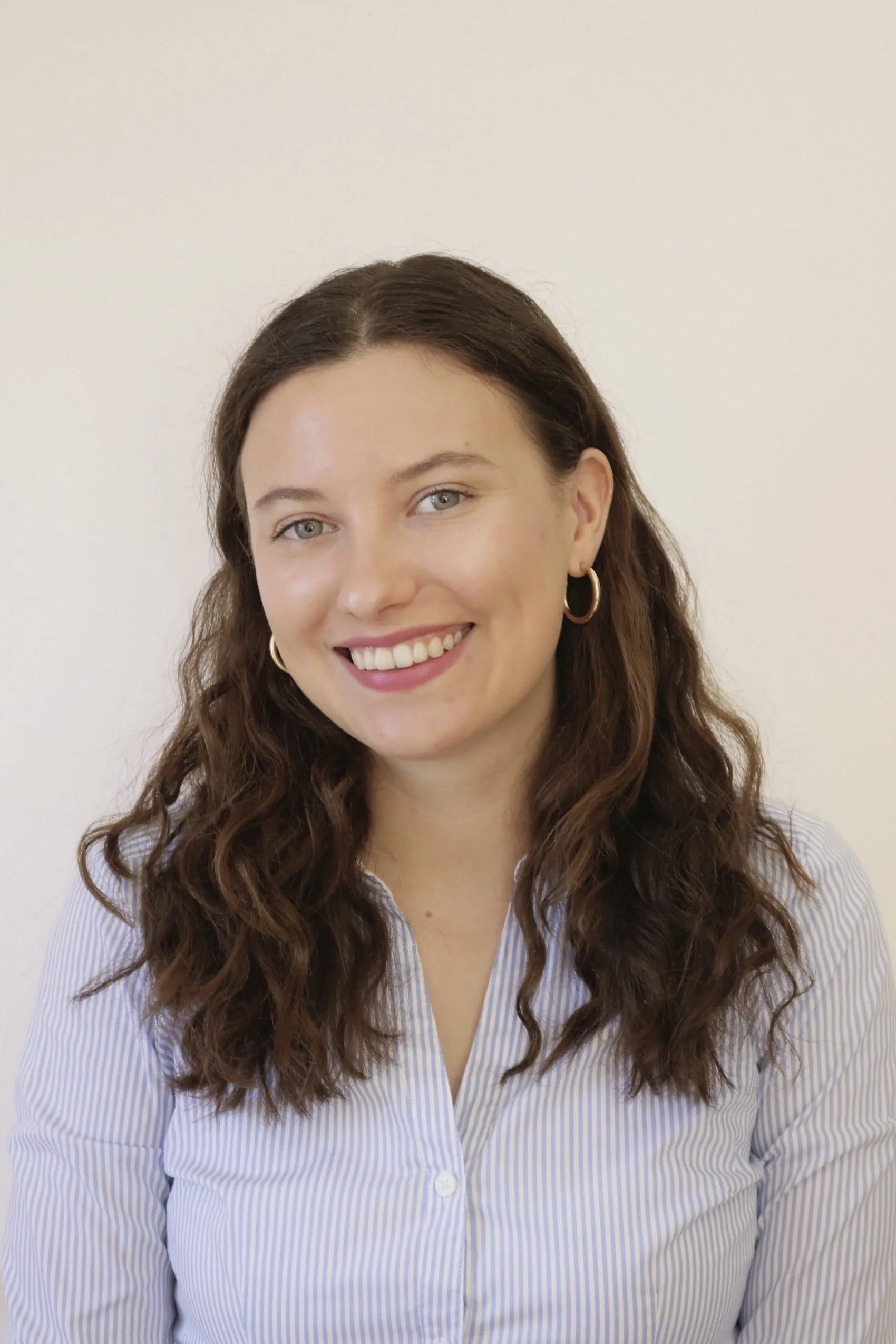 Emma Flessner trägt eine gestreifte Bluse, offenes Haar und lächelt in die Kamera