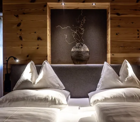 Blick auf das beleuchtete Kopfteil eines Doppelbettes in den Südtirol Chalets Valsegg