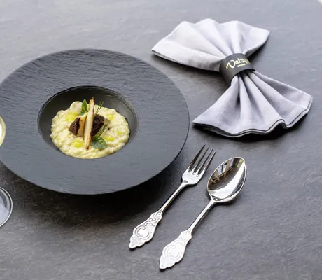 Kunstvoll dekoriertes Gericht auf schwarzem Teller aus dem Restaurant der Südtirol Chalets Valsegg