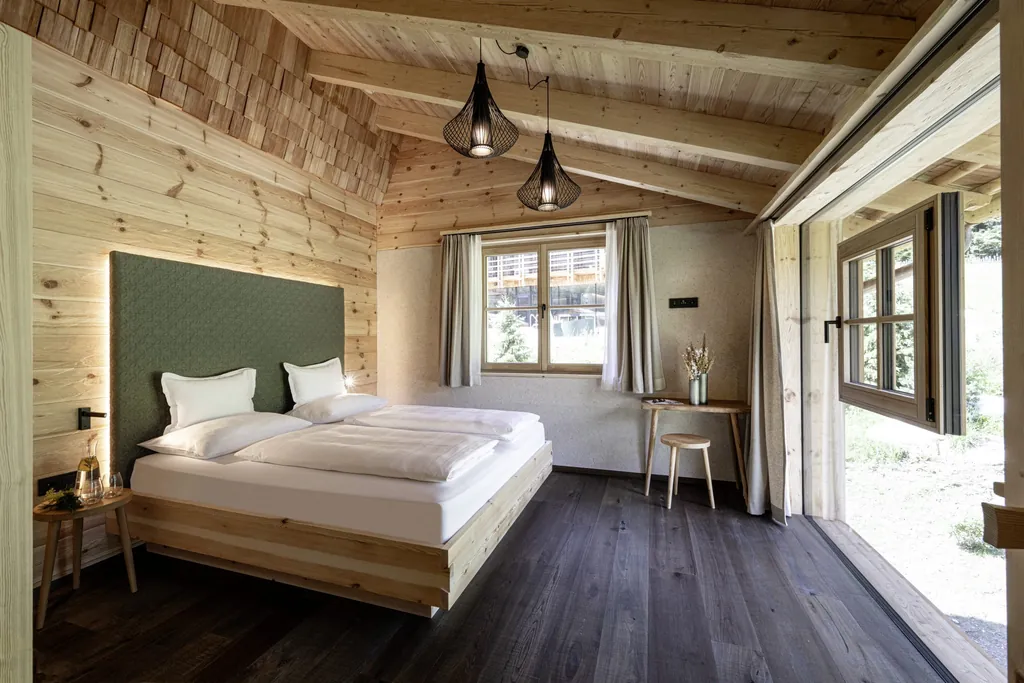 Modern eingerichtetes Schlafzimmer mit vielen Holzelementen, Doppeltbett und bodentiefer Fensterseite in den Südtirol Chalets Valsegg