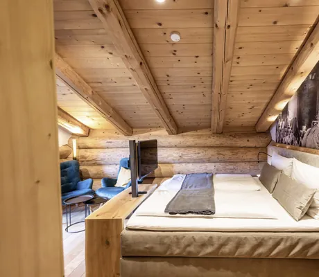 Blick in ein Schlafzimmer mit Doppelbett im Naturstammhaus der Beim Waicher Chalets & Apartments