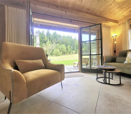 Neu gestalteter Wohnbereich mit Sessel, Sofa und Holzterrasse vor den Fenstertüren