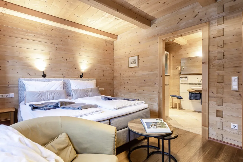 Schlafzimmer im Holzhausstil mit Boxspringbett und T&uuml;r Richtung Badezimmer