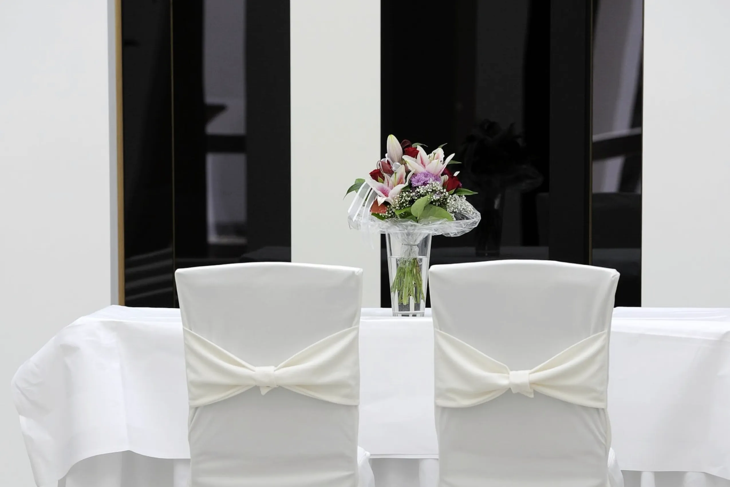 Wei&szlig;e Bestuhlung f&uuml;r das Hochzeitspaar im Schloss Hohenkammer mit Blumenstrau&szlig; auf dem Tisch