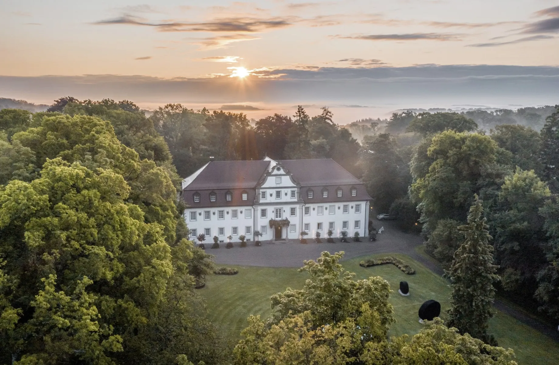 Wald- & Schlosshotel Friedrichsruhevon oben gesehen inmitten der Natur im Abendlicht