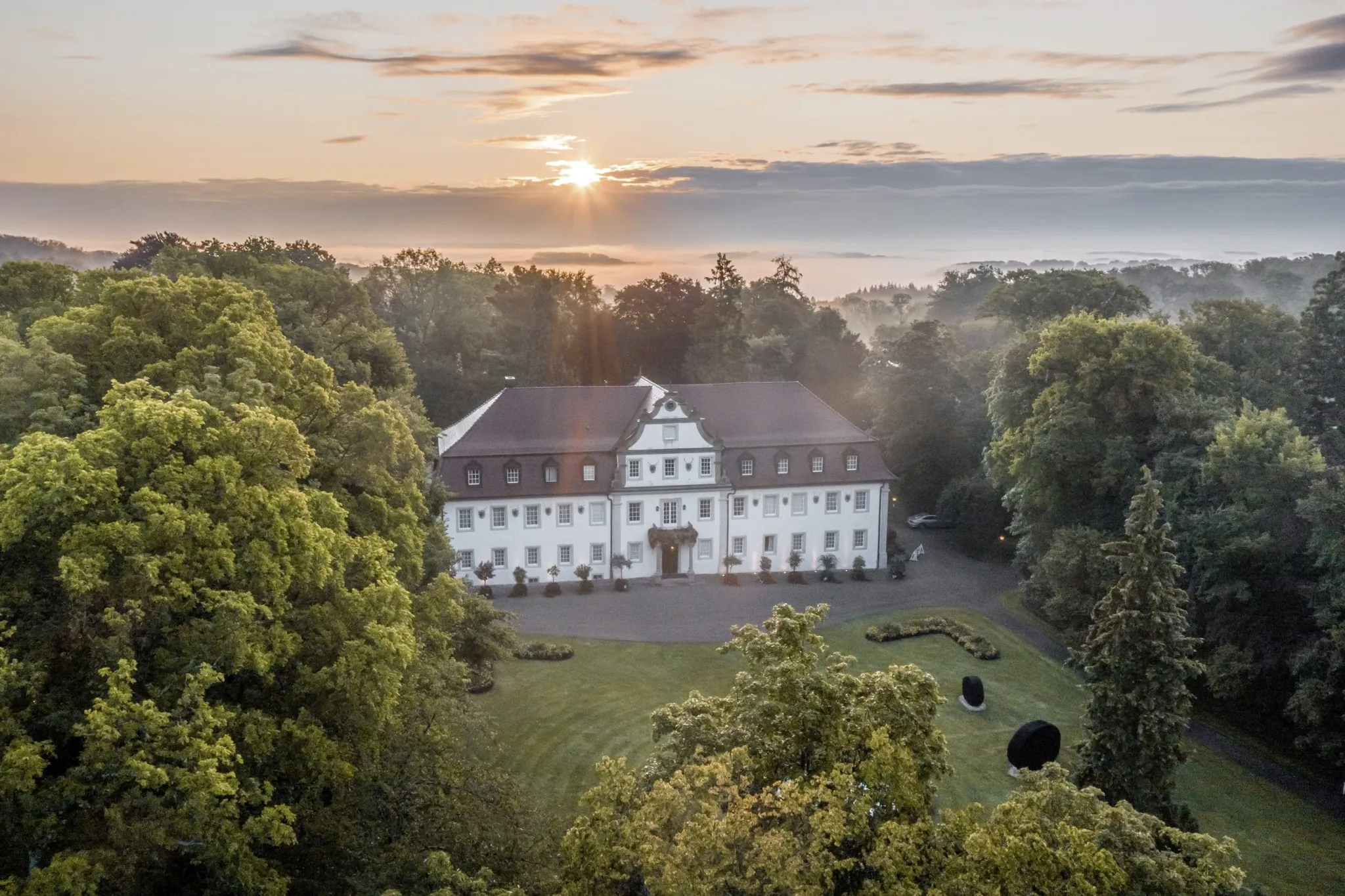 Wald- & Schlosshotel Friedrichsruhevon oben gesehen inmitten der Natur im Abendlicht