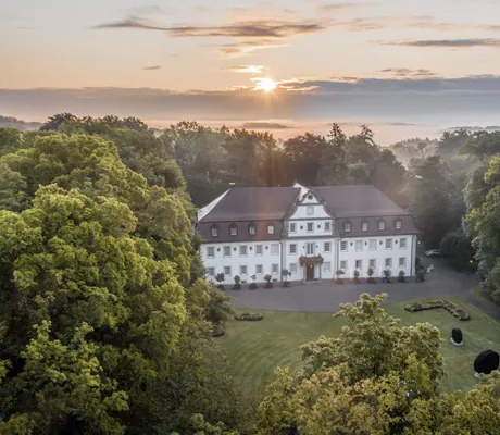 Wald- & Schlosshotel Friedrichsruhevon oben gesehen inmitten der Natur im Abendlicht