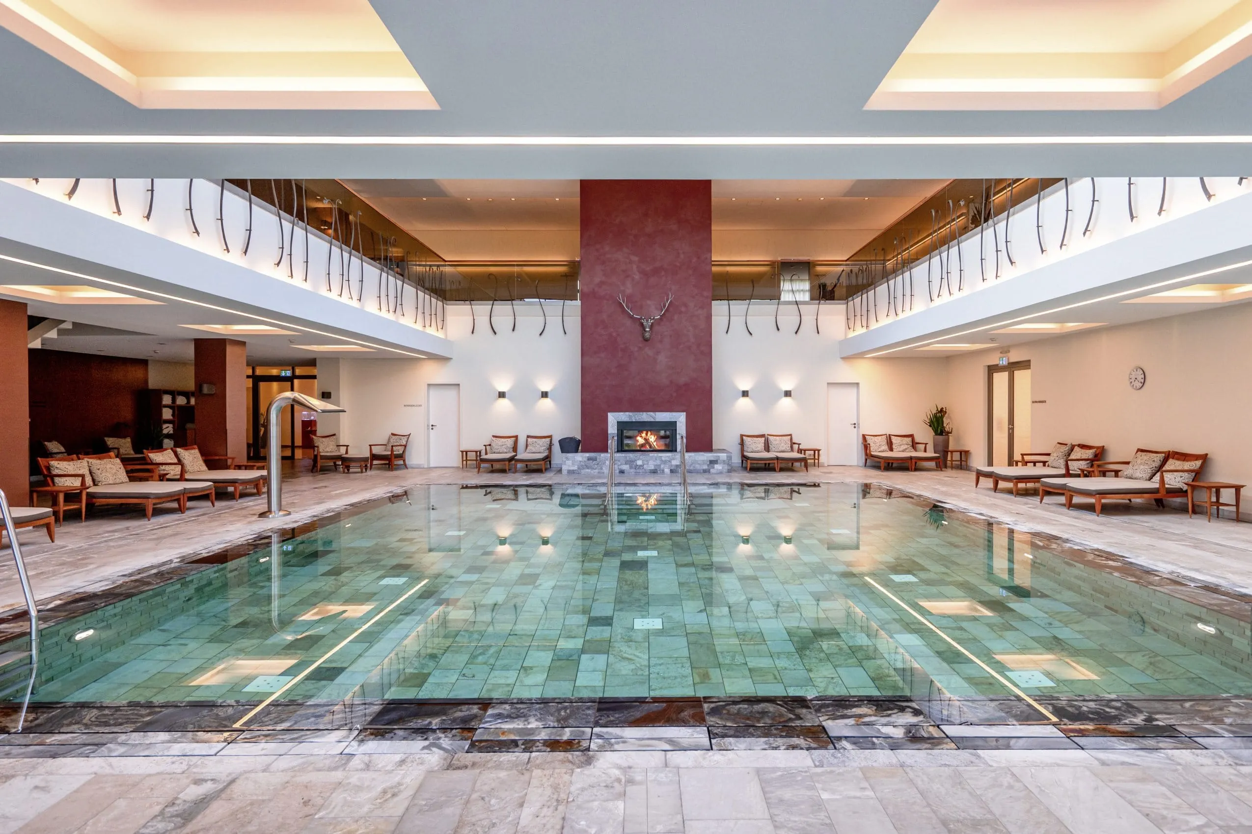 Beleuchteter Indoor-Pool mit Liegen und Kamin im Hundehotel Wald- & Schlosshotel Friedrichsruhe
