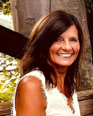 Autorenporträt Jaqueline Schaffrath lächeldn mit weißem ärmellosen Spitzenoberteil in der Natur