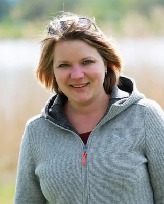 Autorenporträt Katharina Becker lächelns mir Sonnenbrille im Haar und grauer Kapuzenjacke