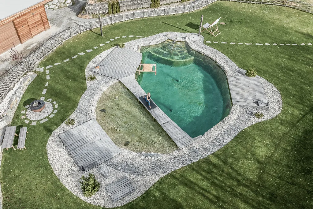 Blick auf den Naturbadeteich mit Steg in der Mitte im Benglerwald – Berg Chaletdorf