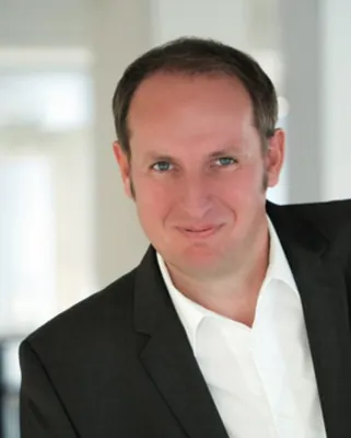 Autorenporträt Mathias Hansen lächelnd mit weißem Hemd und Jackett