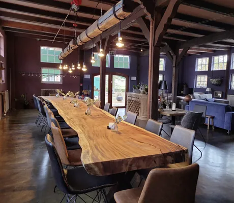 sehr langer Holztisch unter dem Dach mit vielen Lampen an einem Balken in Gut Thansen