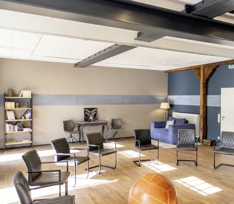 Stuhlkreis mit grauen Lederstühlen und Medizinball vor blauer Wand im Gut Thansen