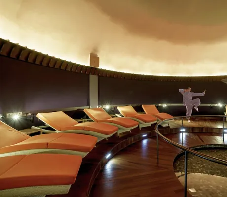 runder Ruheraum mit orangen Liegen und Mönch im Posthotel Achenkirch