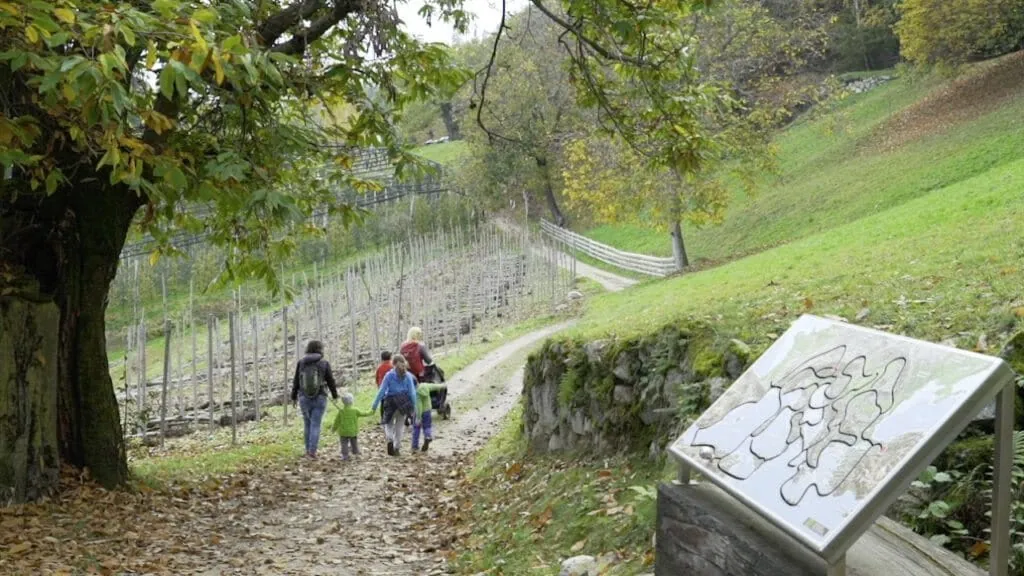 Familie wandert Wanderweg hinunter in herbstlicher Landschaft beim Törggelen