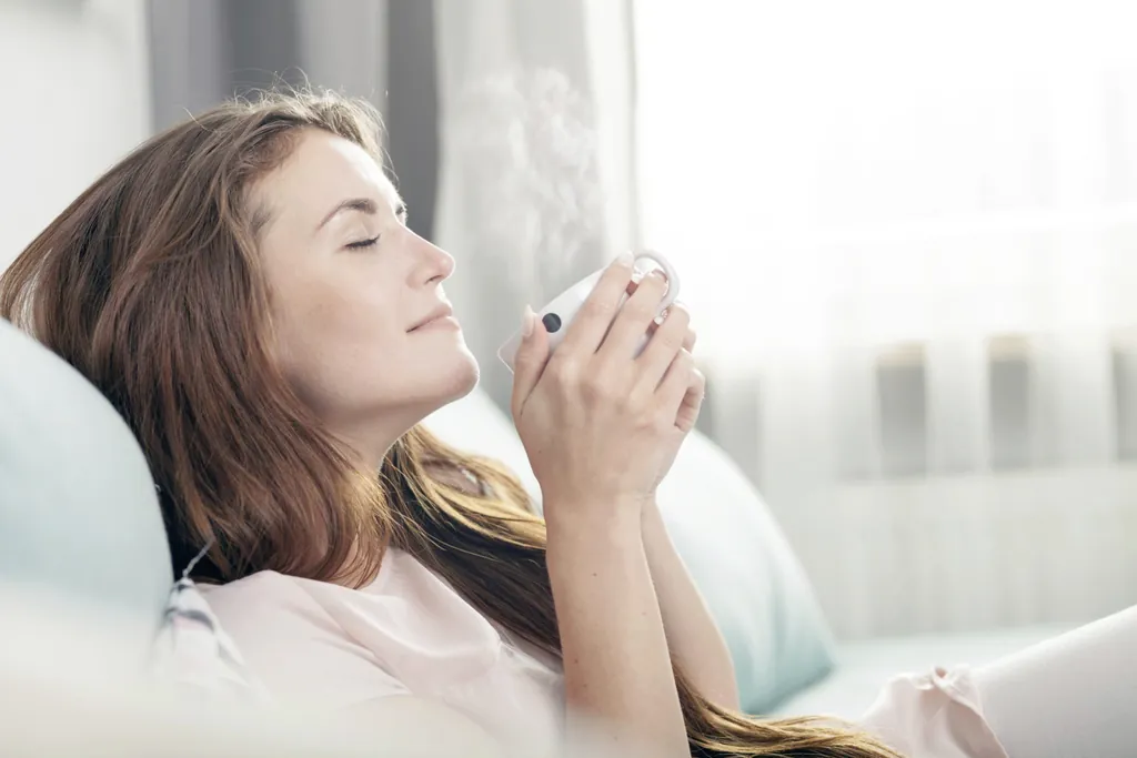 Eine Frau genießt eine Tasse Tee auf dem Sofa