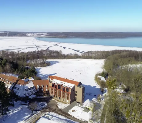 Ansicht des Hotel Bornmühle von außen und oben mit Blick auf den Tollensesee im Winter